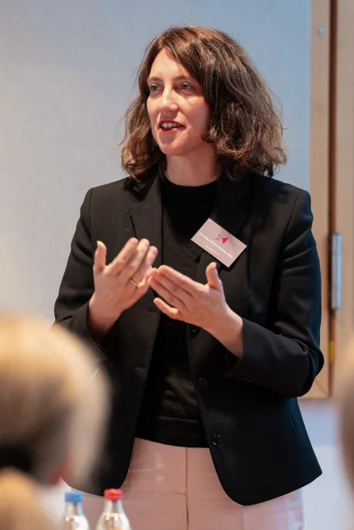 Dorothea Kliche-Behnke in schwarzem Blazer spricht gestikulierend vor einer Gruppe.